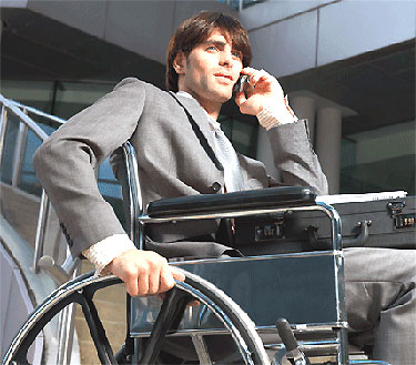 Un jeune homme en fauteuil roulant pourra franchir les marches devant un bâtiment grâce à un matériel d'accessibilité adapté
